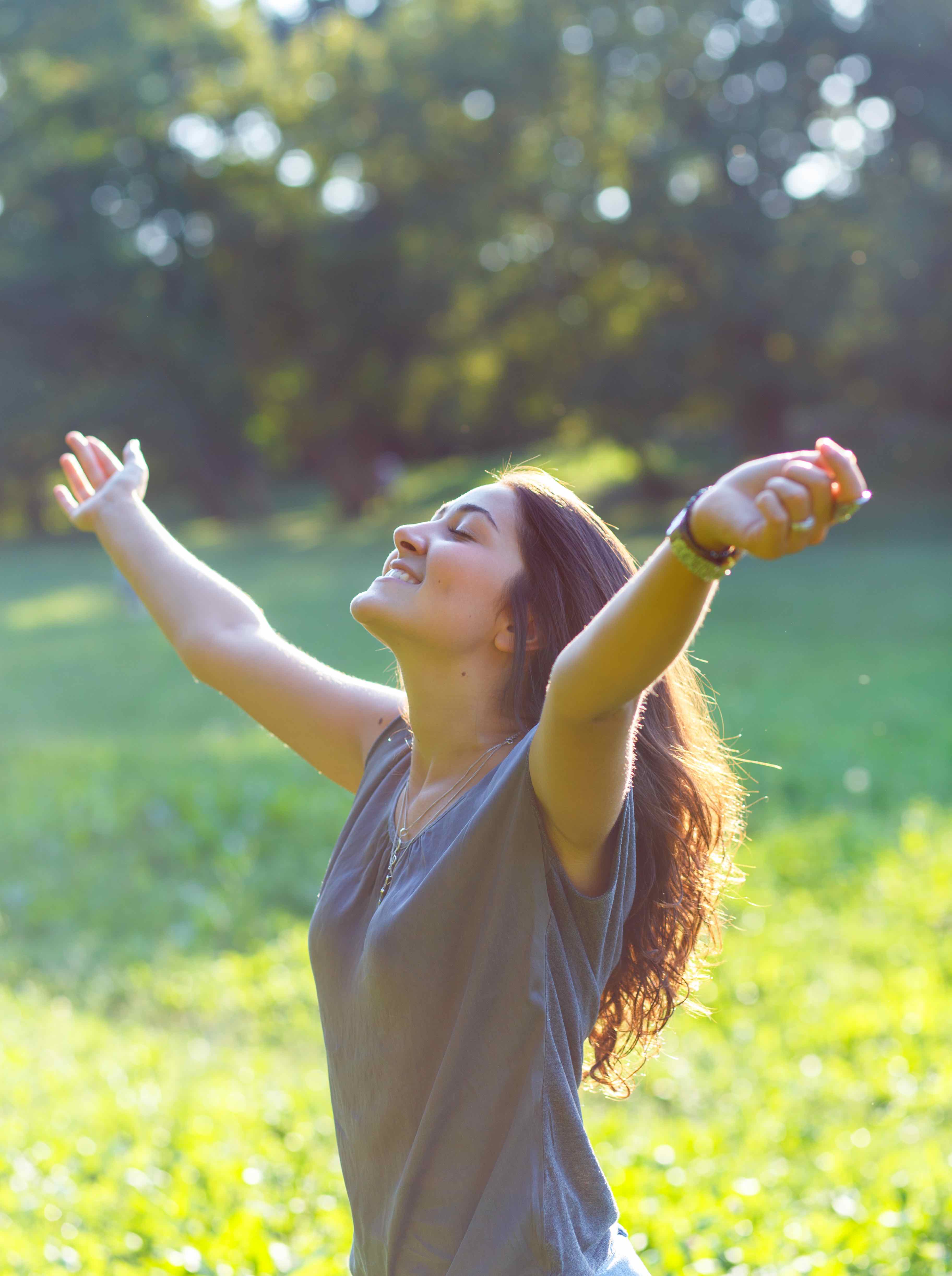 Woman enjoying the outdoors, arms raised in sunlight